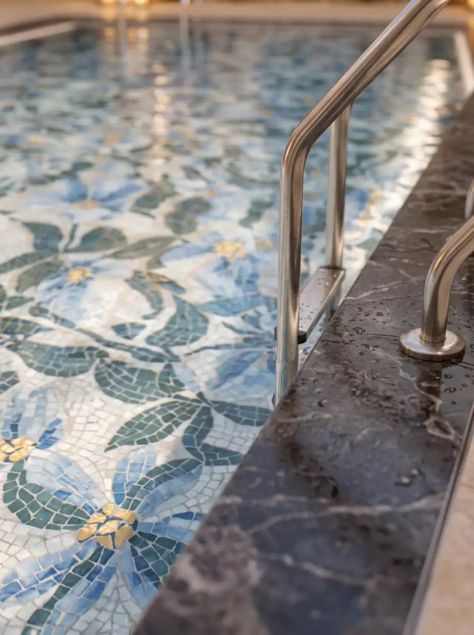 Pool edge with a floral mosaic and a brass handrail