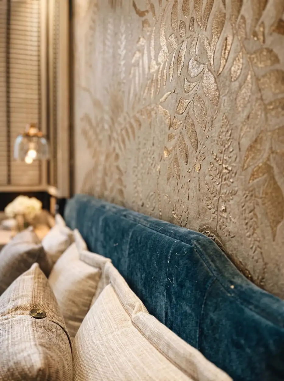 Teal velvet headboard against a pearl-textured wall
